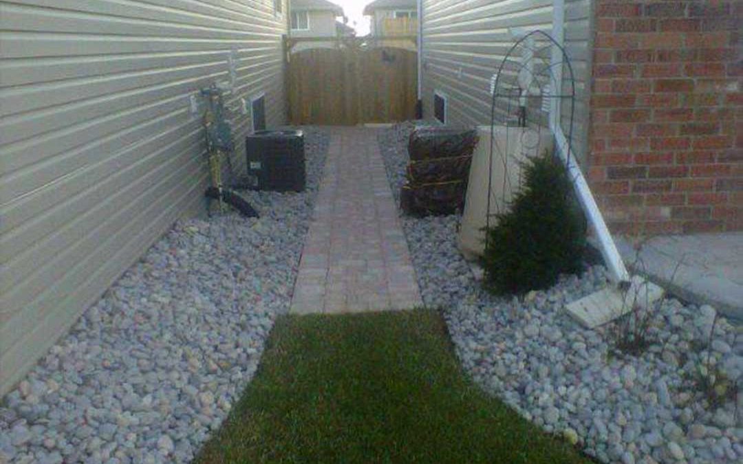 landscape construction between two houses including interlocking stone pathway leading to wooden gates