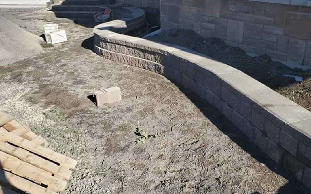 landscape construction of stone retaining wall and steps in front of residence